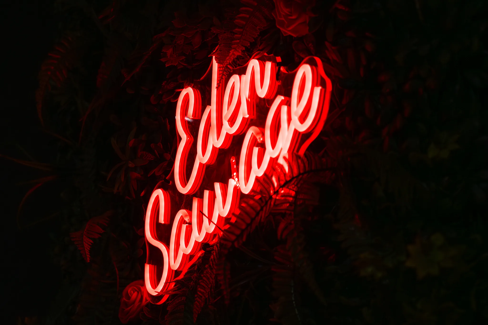 Enseigne néon Eden Sauvage sur mur végétal – photo LLP Agency