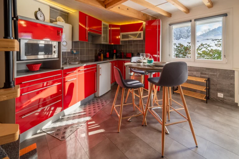 Cuisine rouge équipée avec coin repas – photo LLP Agency