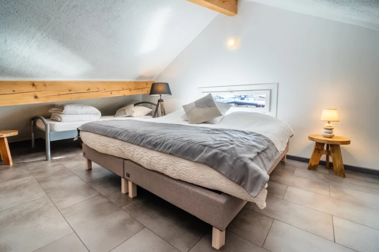 Chambre avec lit double et linge gris – photo LLP Agency